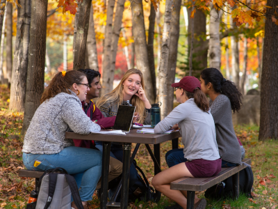 Students sitting at picnic table in the fall